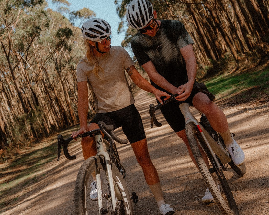 Two riders on a forest gravel road in the Enduro Tee and the Enduro Mesh Tee