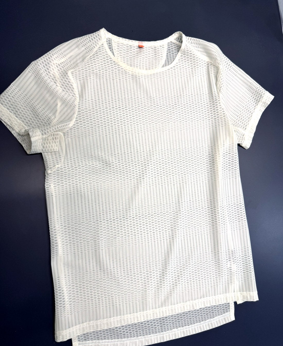 The first Enduro Mesh Tee sample in white open diamond mesh, laid flat
